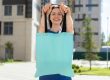 Donna sorridente che mostra una shopper, enfatizzando il suo design e la praticità.